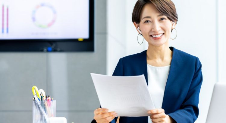 書類を見ながらにこやかに仕事をする女性ビジネスマン